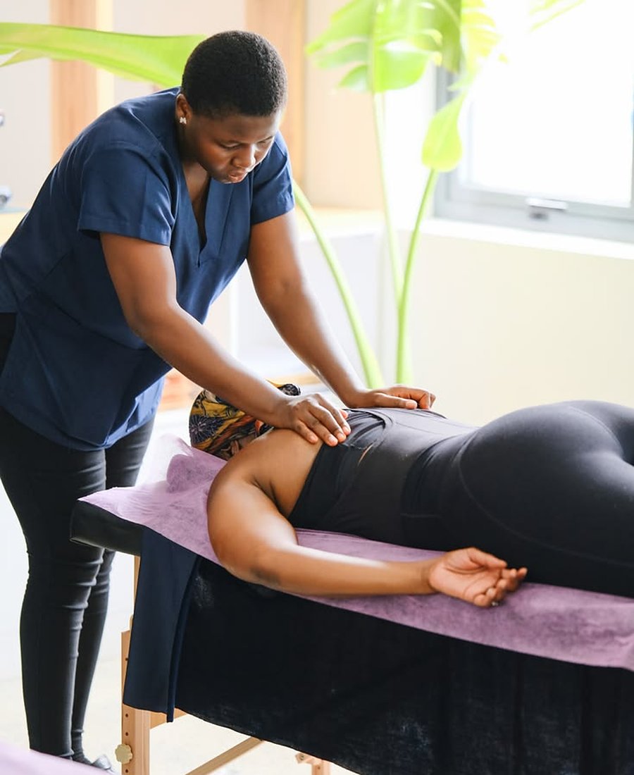 Physiotherapist treating a woman lying on a treatment table at home